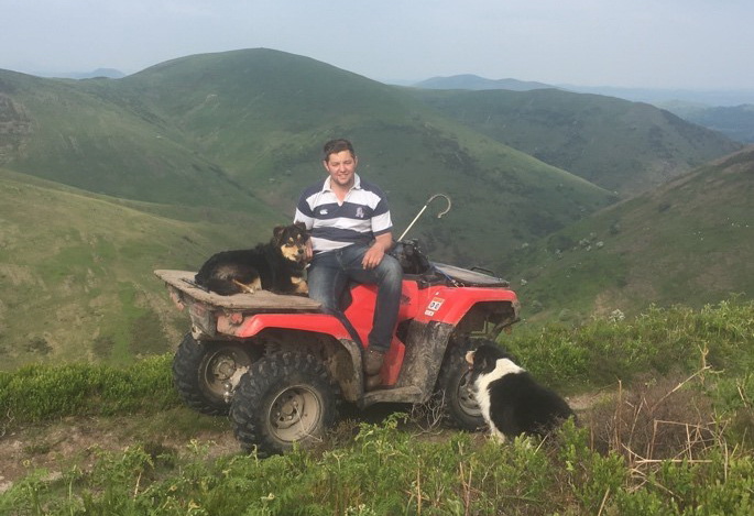 Tom Lloyd sat on quad bike with his sheepdogs on the Long Mynd